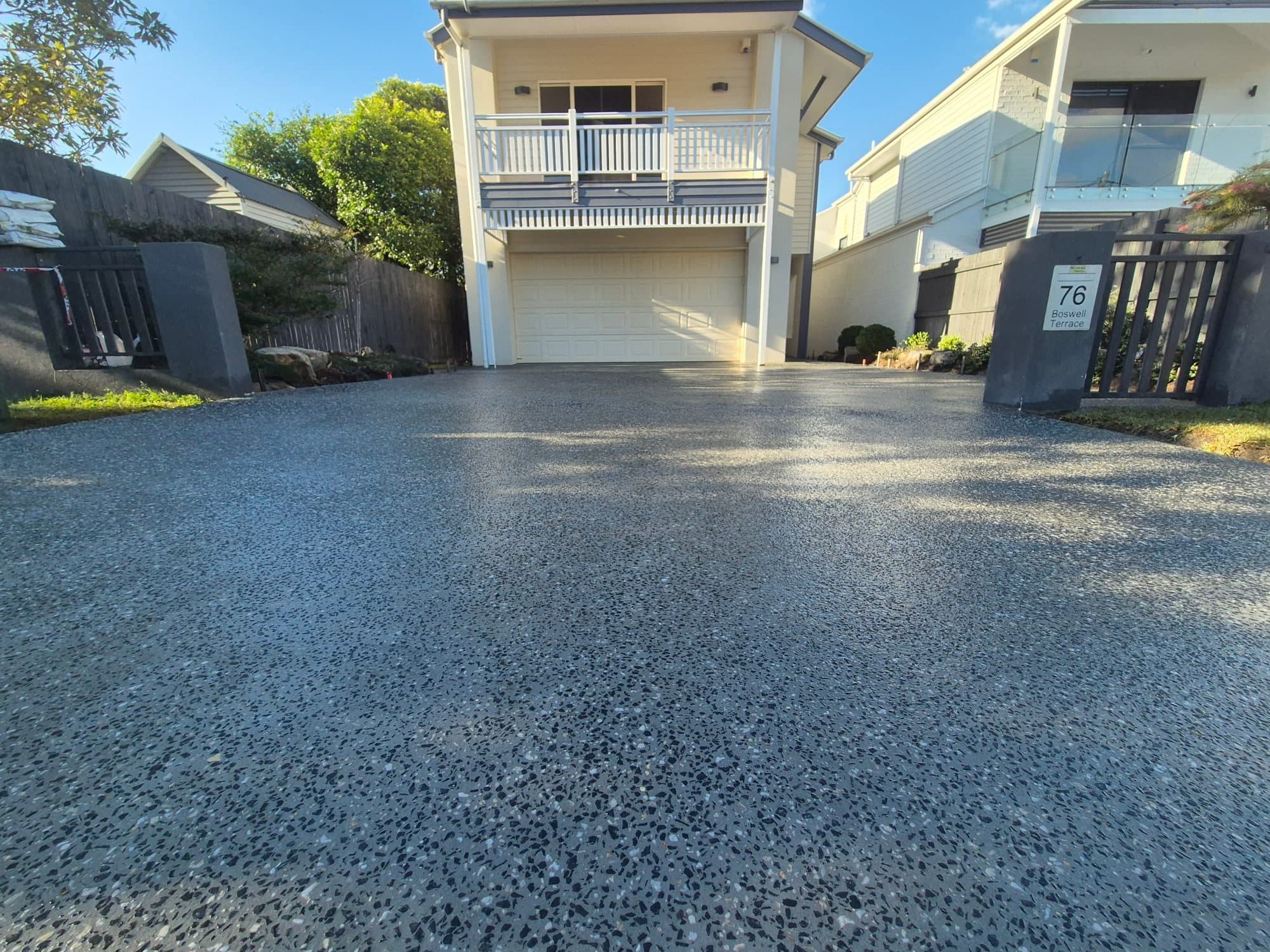 Exposed aggregate concrete driveway leading to a two-storey home